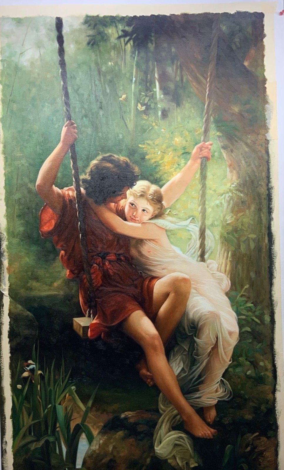 A copy after Pierre-Auguste Cot of a young couple seated together on a rope swing in dappled woodland light.