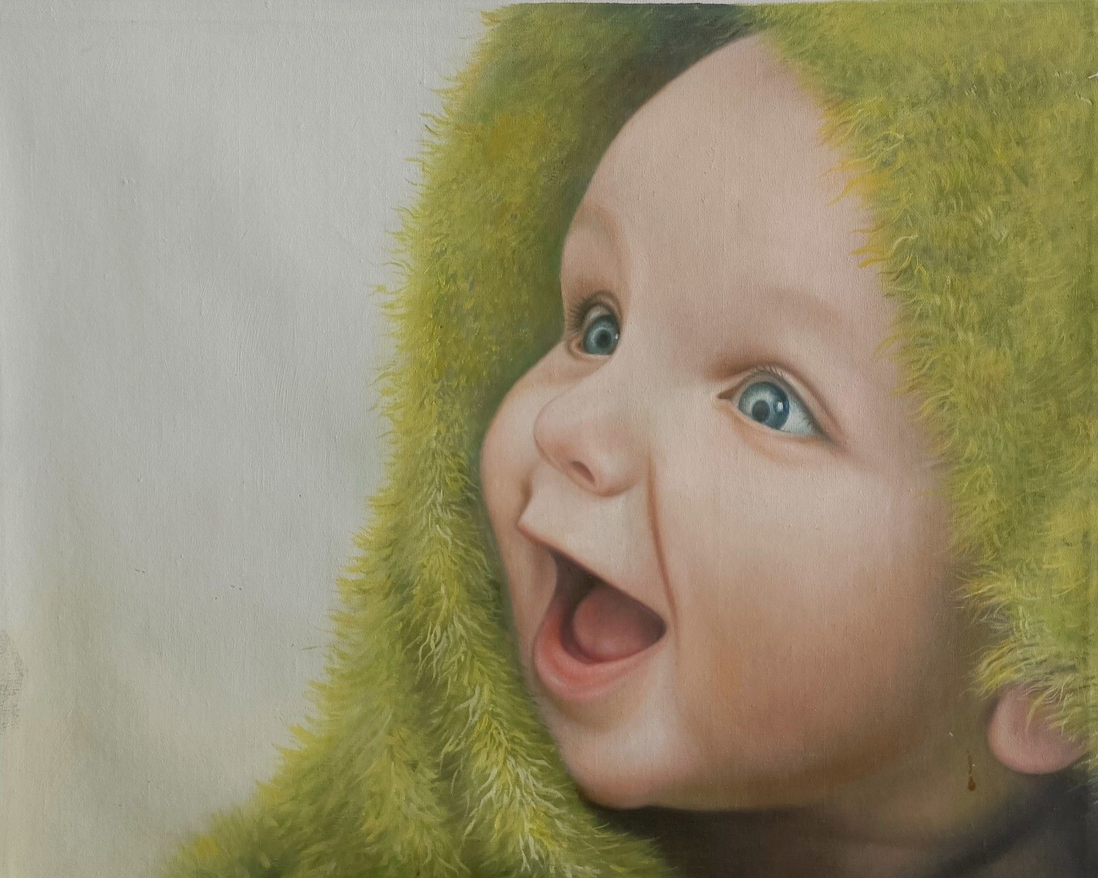 A smiling baby looking upward from a soft green hood.