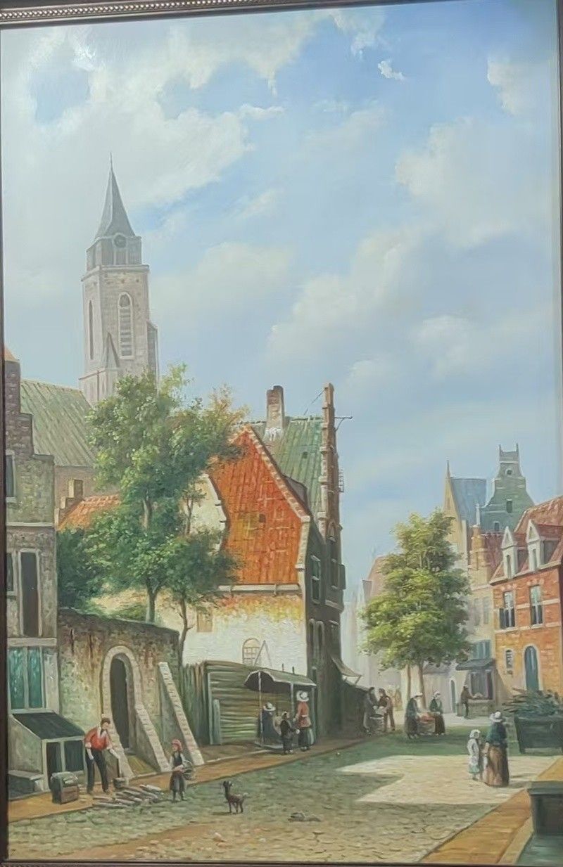 A narrow old town street with a church tower, small figures, and stone buildings fills this framed scene.
