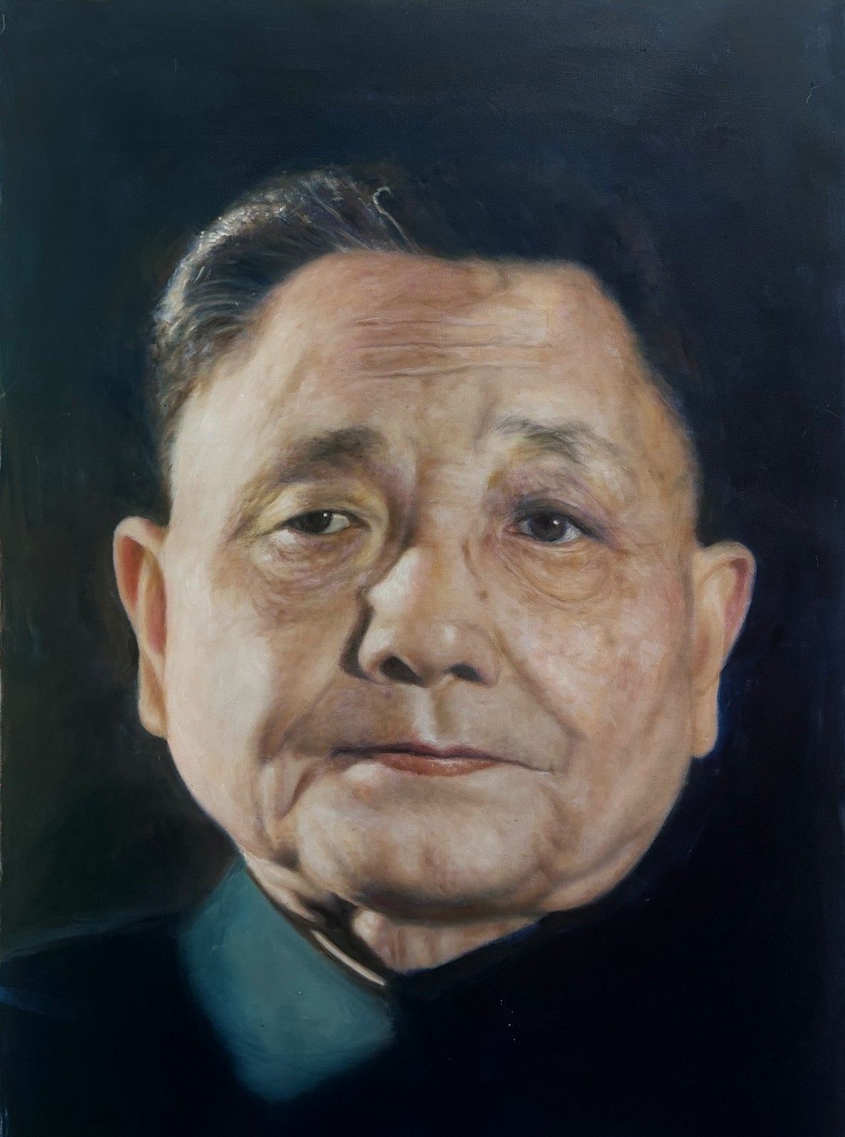 An elderly man with grey hair and a dark collared jacket against a dark background.